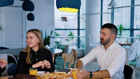 cheerful and happy conversation of colleagues during lunch break. people sit at table having meal and laughing.