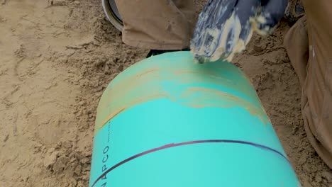 construction worker spreading pipe lube - grease on the end of a sewer pipe in preparation for assembly