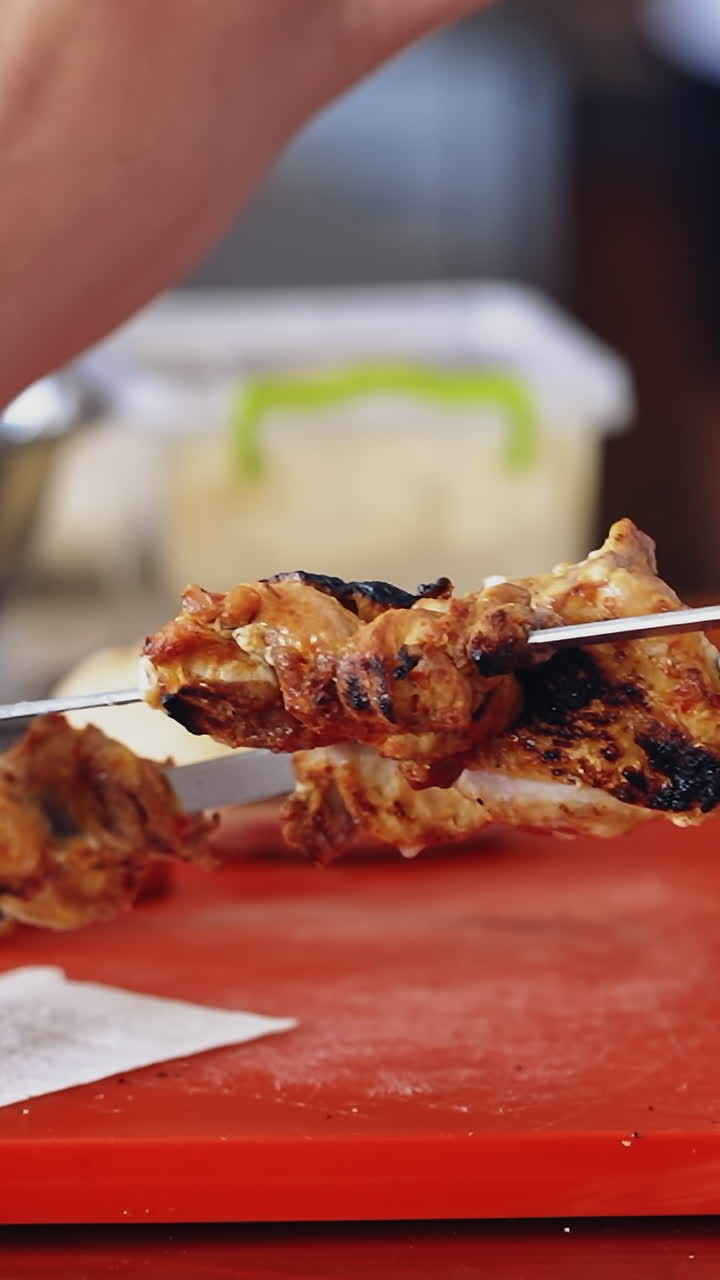 Chef puts ready barbeque. Cook takes roasted juicy meat from skewers and puts on a dish. Tasty shashlik ready to eat in the restaurant. Vertical video