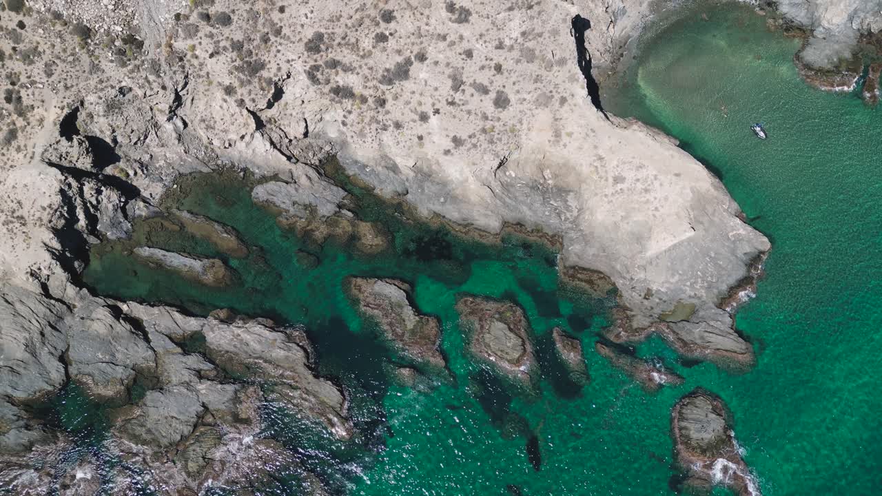 Top-down aerial view of the rocky coastline and clear turquoise waters near Almería in the Andalucía region of Spain, showing dramatic shore formations and vibrant Mediterranean colour