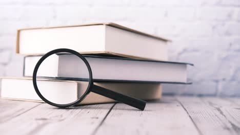 books and magnifying glass on wooden table