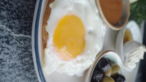 close-up of a fried egg and breakfast items with olives