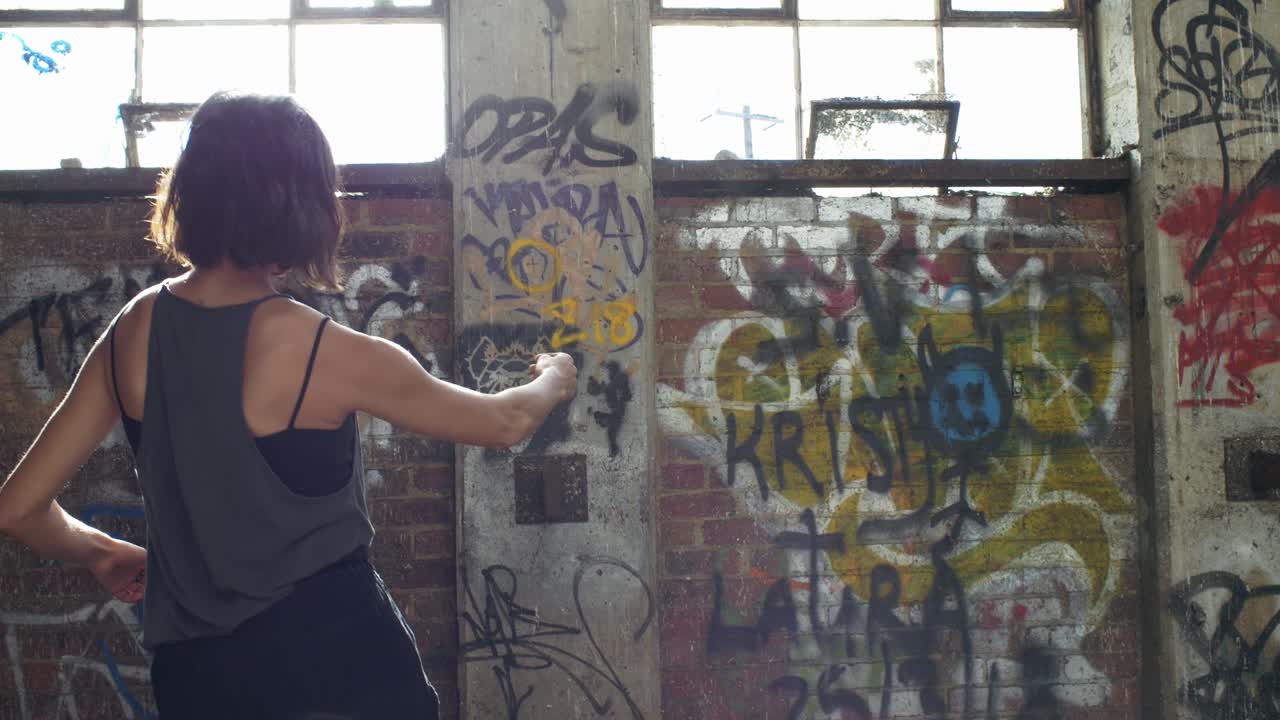 Donna che si esercita in passi di danza in un magazzino con pareti graffitate - piano medio