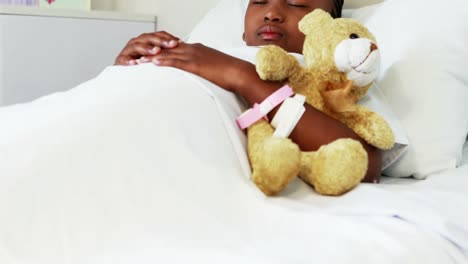 Sick-girl-resting-with-teddy-bear-on-bed