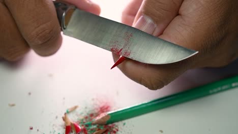 Footage-of-hands-slowly-sharpening-a-pencil-and-some-coloured-pencils-with-a-sharp-knife