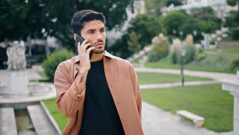 Chico-Serio-Llamando-Al-Parque-Telefónico-Primer-Plano-Vertical.-Hombre-Hablando-Por-Teléfono-Esperando