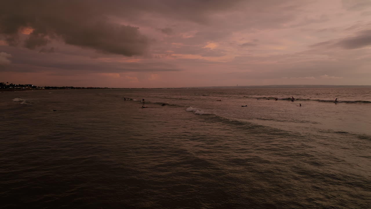 인도네시아 발리 주 쿠타 우타라의 구 해변에서 서퍼들과 함께 열대 바다에서 해가 지는 모습