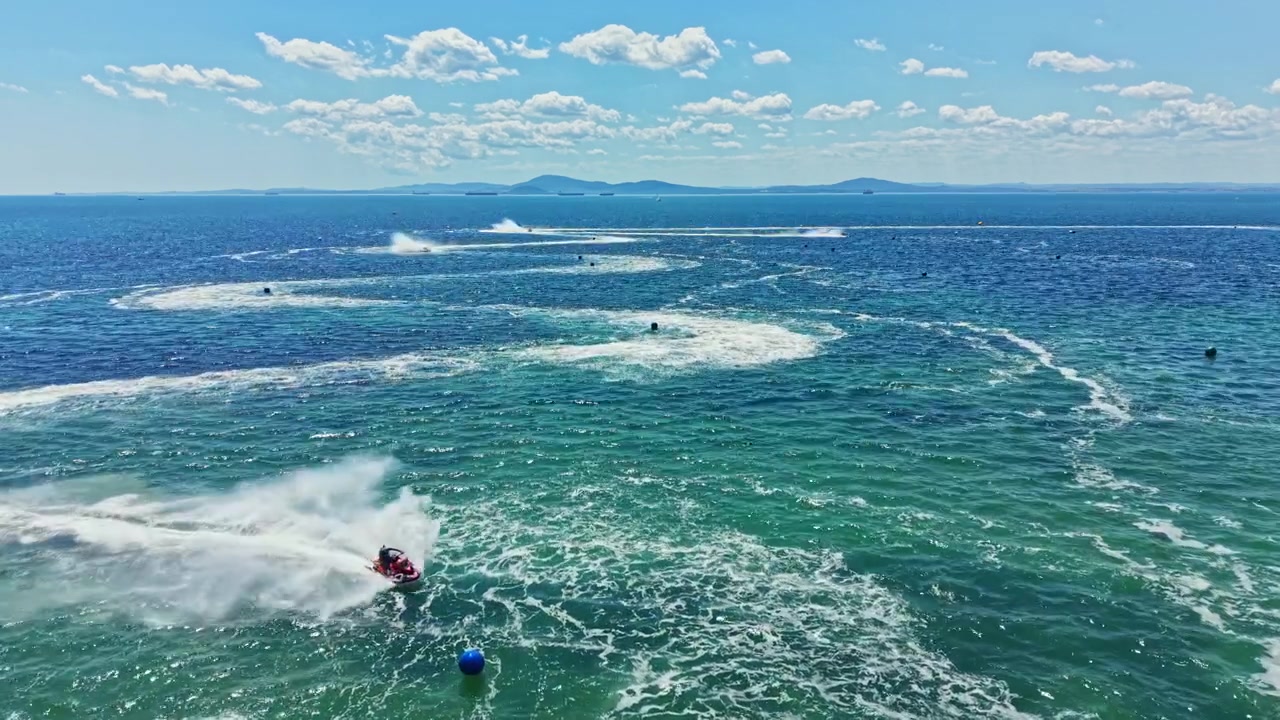 Jet ski racing takes place on a sunny day with clear skies over the blue water
