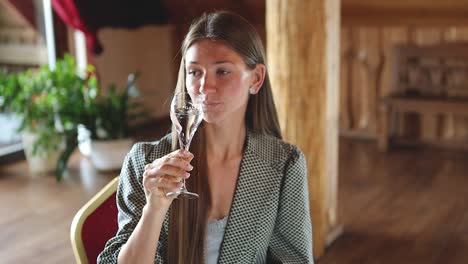 young caucasian woman drinking champagne at the restaurant dinner table inside