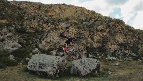 motorcycle acrobat shows trick on rocks fpv. skilled sportsman in helmet performs motorbike maneuver at highland. extreme sport lover hobby