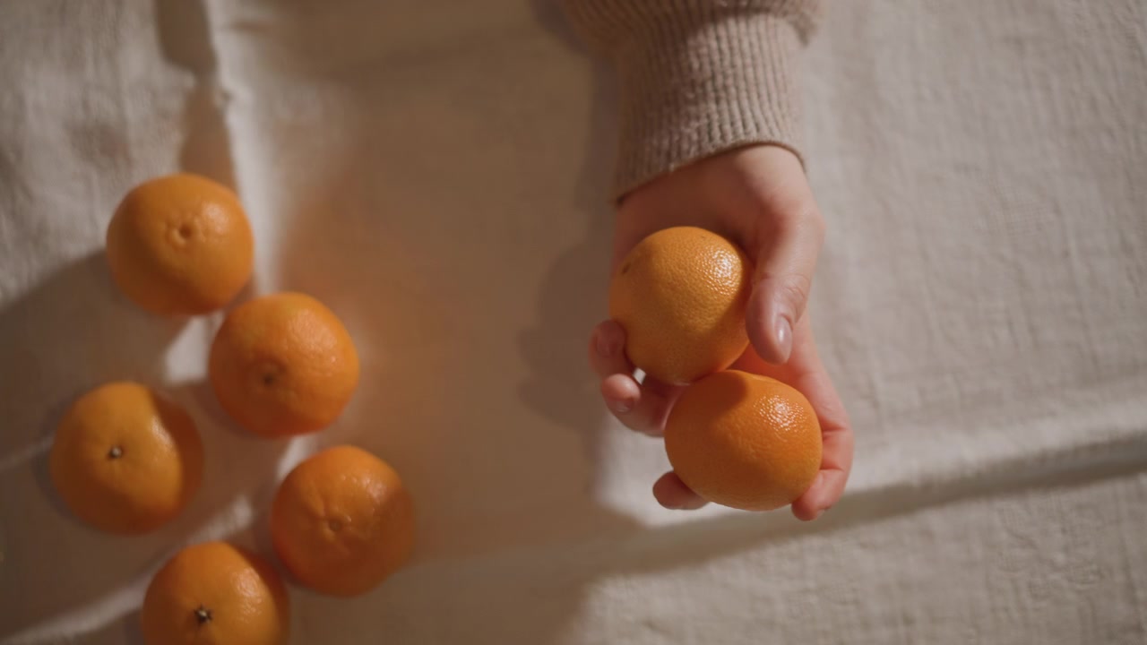 Mão arrumando tangerinas em mesa de linho, estilista de alimentos organizando frutas cítricas maduras em um arranjo agradável, luz natural suave, tons quentes, casca texturizada e cacho de frutas espalhadas, composição minimalista e calma