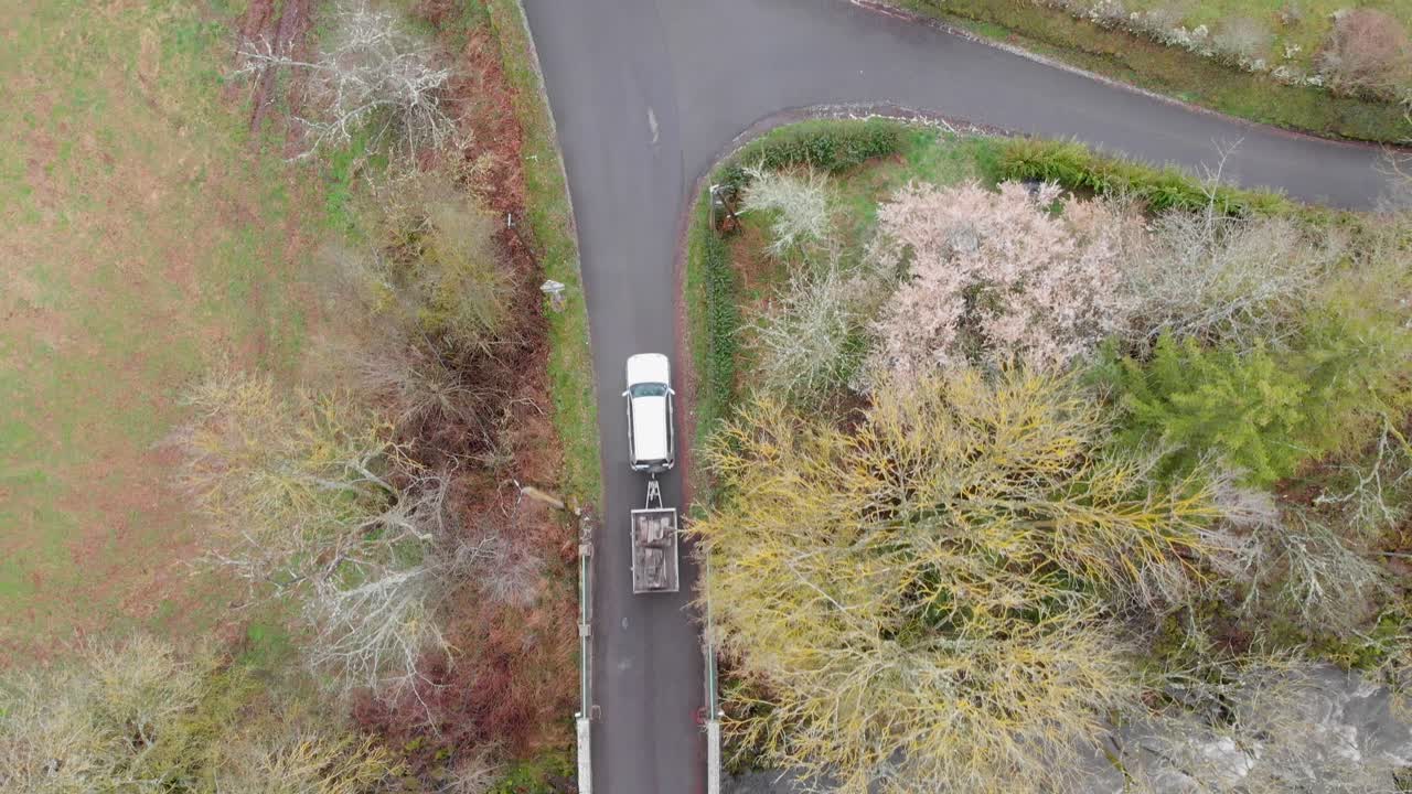 Aerial View of a Car with Trailer Crossing a Rural Bridge Over a River