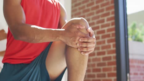 hombre afroamericano en forma haciendo ejercicio en casa y estirándose en casa