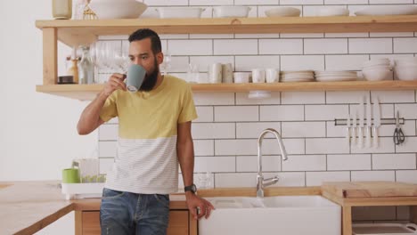 Handsome-man-drinking-coffee-in-the-kitchen