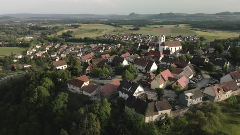 drone footage orbits leftwards around aach village from a new angle, highlighting the church tower and the charming old town against the scenic backdrop.
