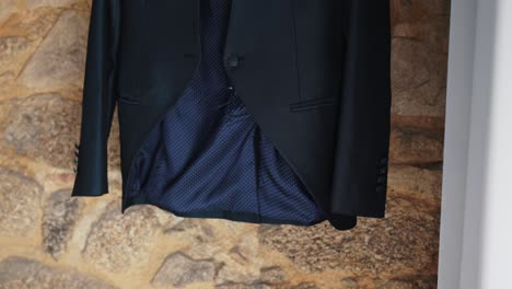 black suit jacket with blue lining on stone wall with soft natural light