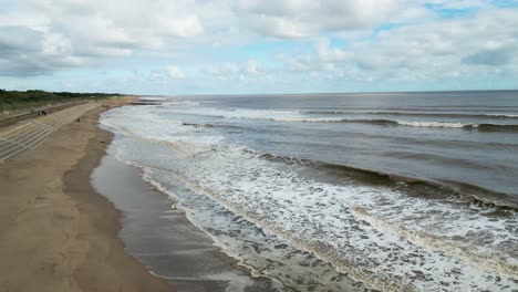 english seaside resort, shot using a drone, giving a high aerial viewpoint showing a wide expanse of sandy beach with a pier and crashing waves-1