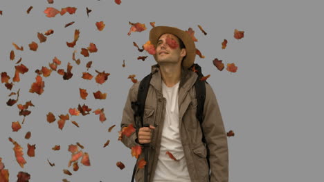 man standing under leaves falling on grey screen