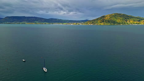 Toma-De-Drones-Del-Lago-Attersee-Con-Barcos-Y-Picos-Montañosos-Con-Espesa-Vegetación.