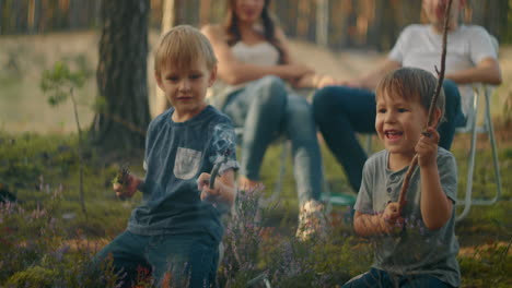 children sit by the fire and look at the fire playing with sticks