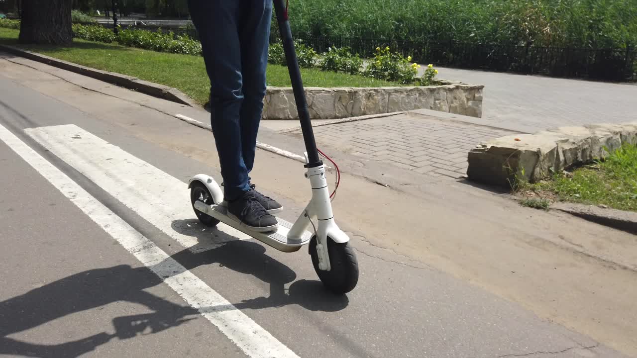 CHISINAU, MOLDAVIA - 9 DE JULIO DE 2019: Hombre montado en un patinete eléctrico blanco en el parque Valea Morilor. Lago al fondo