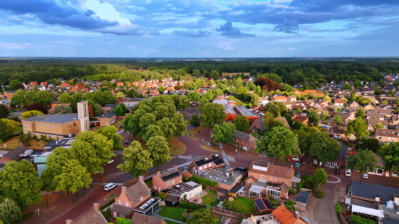 Bird's eye view of a peaceful village. Aerial view captures a serene village landscape with lush greenery, houses, and winding roads under a clear blue sky