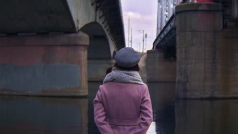 woman under a bridge by a river