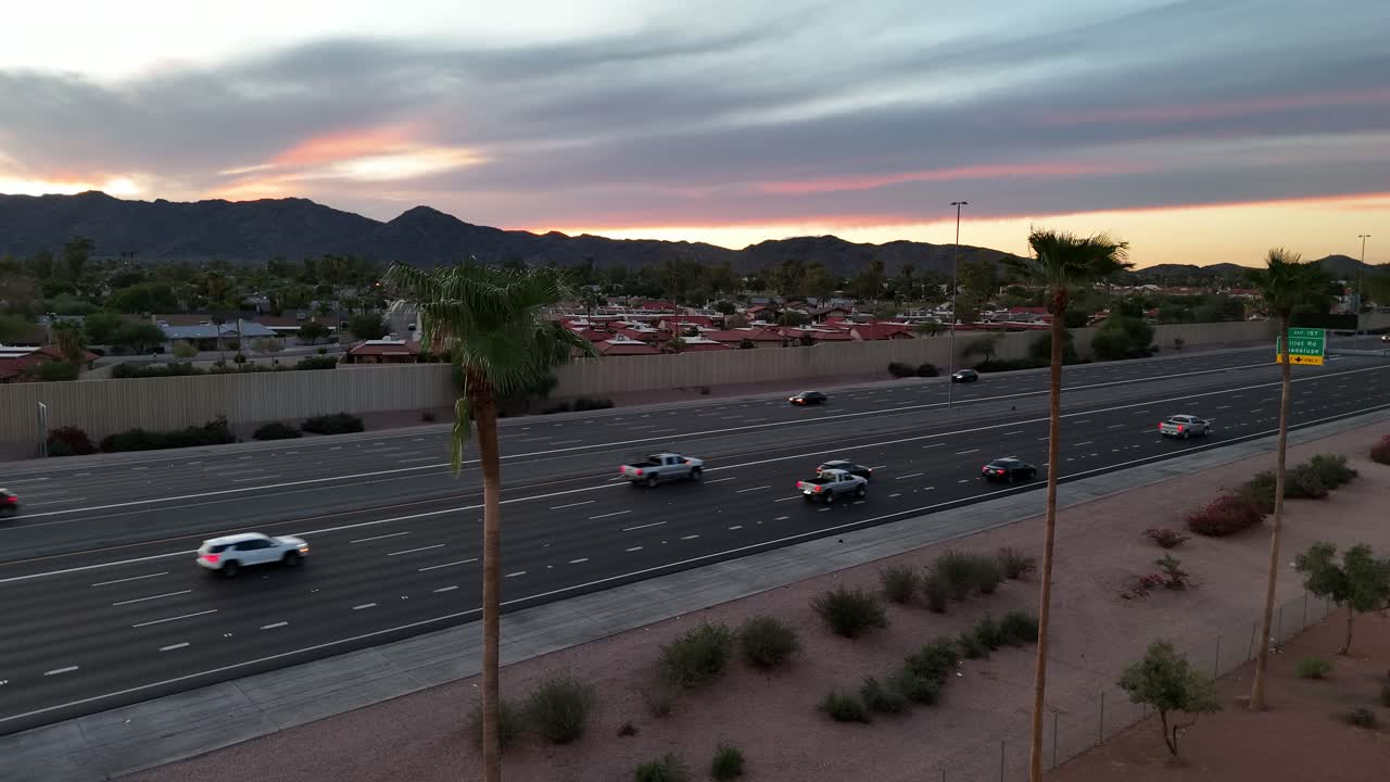 Cars traveling on highway during sunset with mountains in background, Palm Trees in foreground, Interstate 10 in Phoenix Arizona, South Mountain, aerial view, static shot