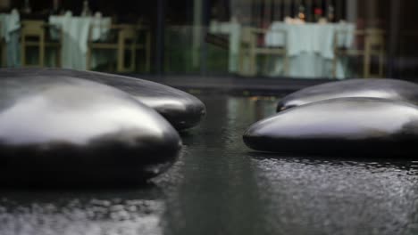 추상적이고 고요한 느낌을 더해주는 반사되는 수면을 갖춘 물 속의 커다란 검은 돌 4개