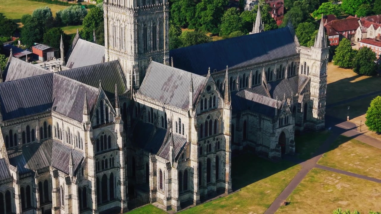 Bliski widok z lotu ptaka na Katedrę w Salisbury, ukazujący średniowieczne kamieniarstwo, gotyckie okna, strome dachy, wieże i historyczne detale architektoniczne w Wiltshire