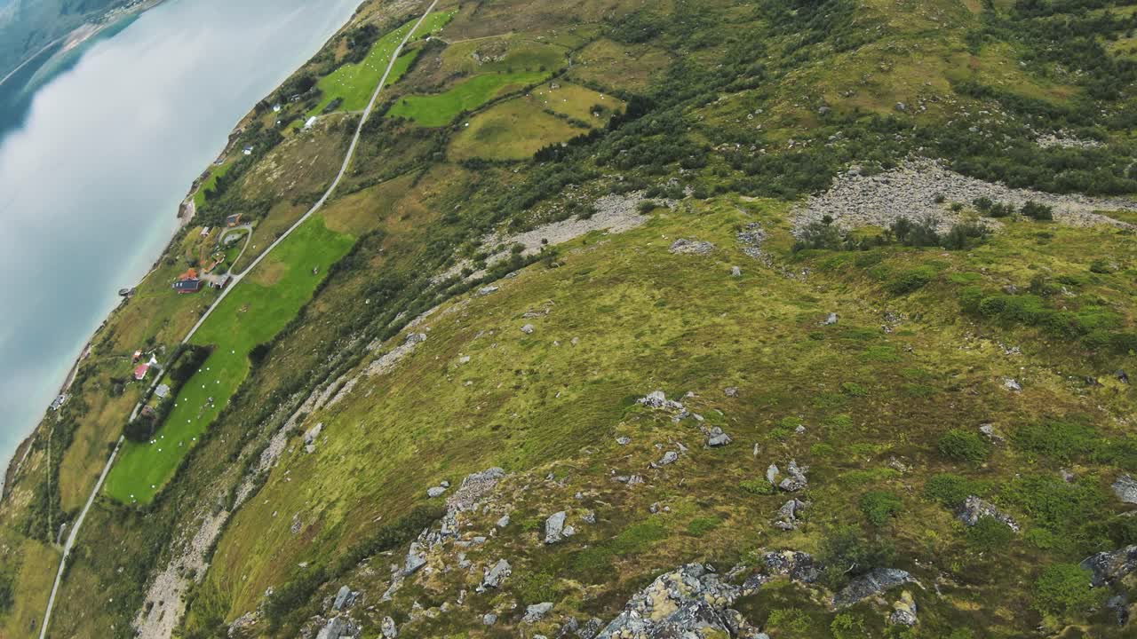 zambullirse en una montaña en noruega con vista al océano y pastos, luego girar para mirar hacia las montañas y un lago en la parte de atrás, en cámara lenta
