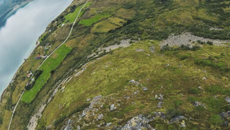 Zambullirse-En-Una-Montaña-En-Noruega-Con-Vista-Al-Océano-Y-Pastos,-Luego-Girar-Para-Mirar-Hacia-Las-Montañas-Y-Un-Lago-En-La-Parte-De-Atrás,-En-Cámara-Lenta