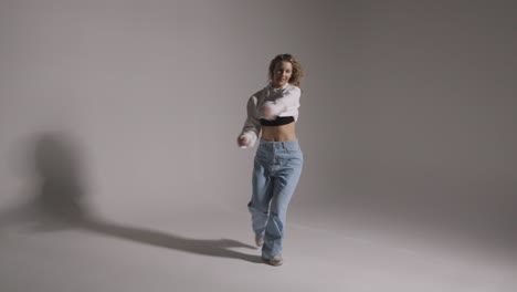 full length studio shot of young woman having fun dancing against grey background 7