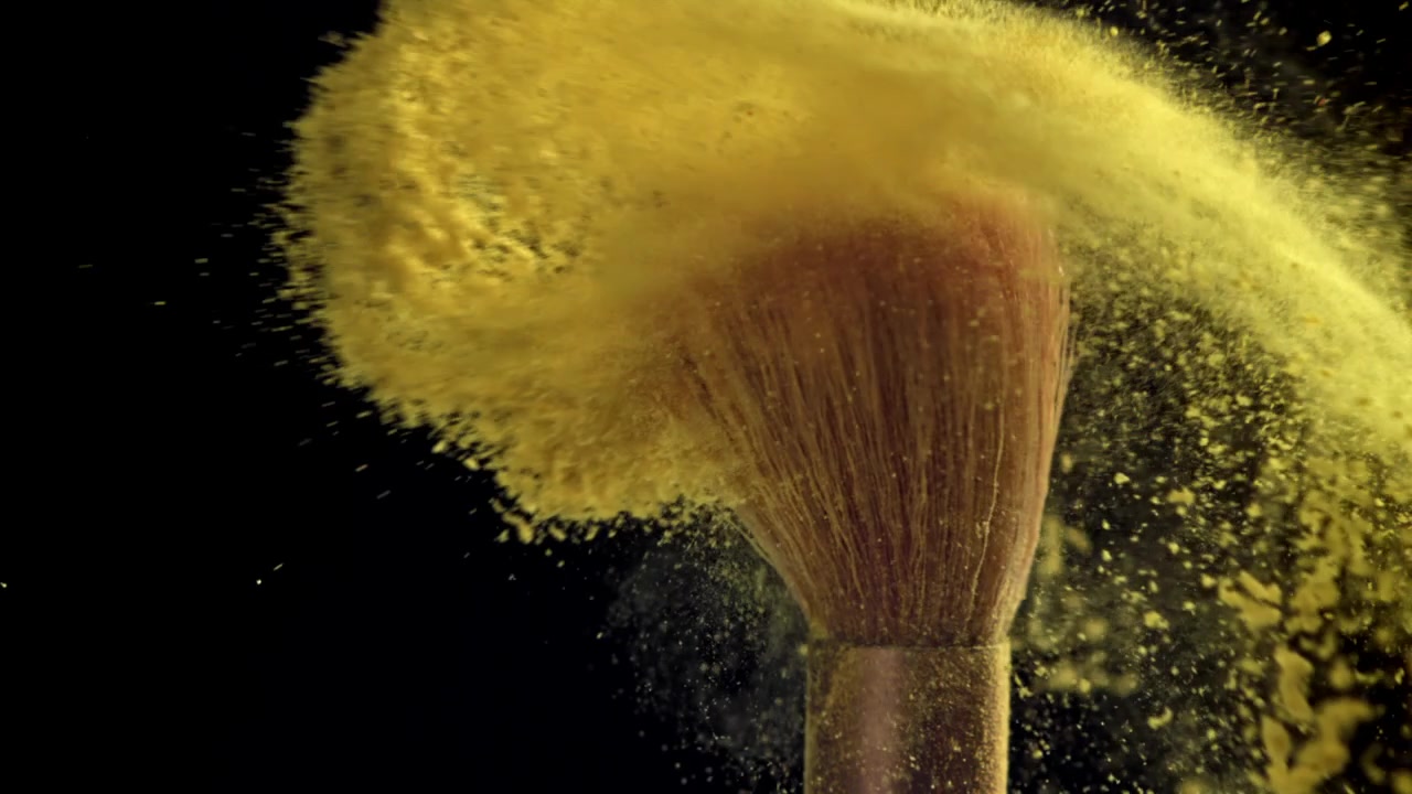 Gult makeuppudder eksploderer fra børster i slowmotion