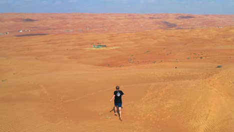 Hombre-Corriendo-Descalzo-En-Las-Arenas-De-Un-Vasto-Y-Estéril-Desierto-Interminable-Con-Un-Controlador-De-Drones-En-La-Mano