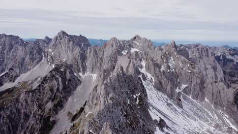 aerial of steep rocky alpine mountain top peaks, epic landscape drone scenery view flying up