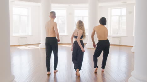 back view of three professional contemporary dancers training dance moves in the studio