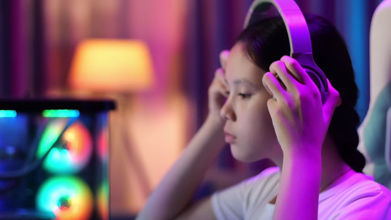 헤드폰을 착용하고 컴퓨터에서 비디오 게임을 시작하는 아시아 십대 소녀 게이머의 클로즈업