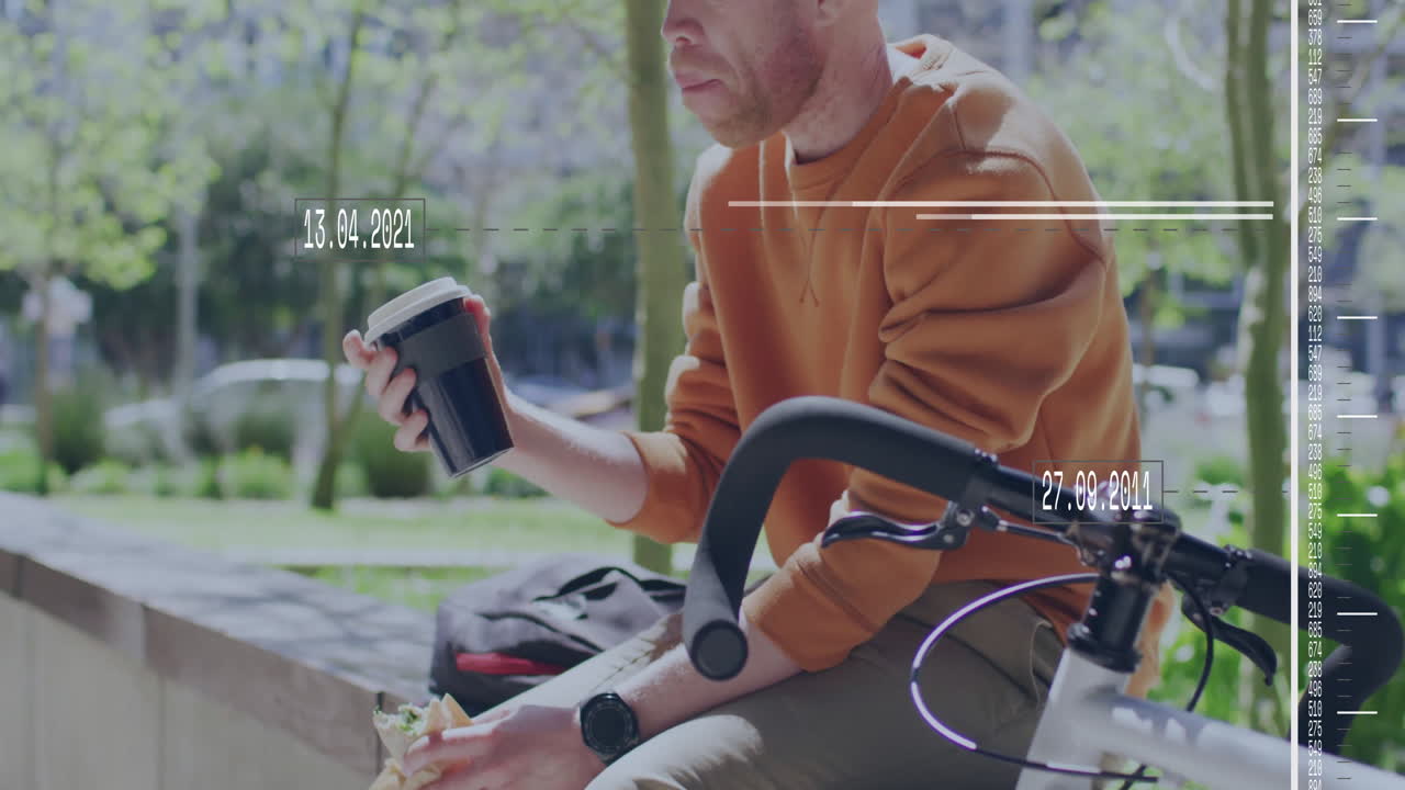 Holding coffee cup and sandwich, man in orange sweater standing by bicycle