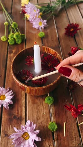 floral arrangement with candle and water in wooden bowl