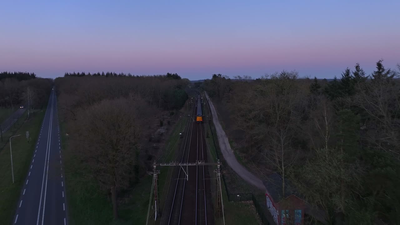 Top Down Shot of Train Speeding Down Railroad Tracks During a Blue Evening Sunset