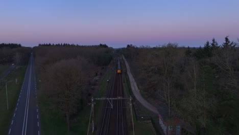top down shot of train speeding down railroad tracks during a blue evening sunset