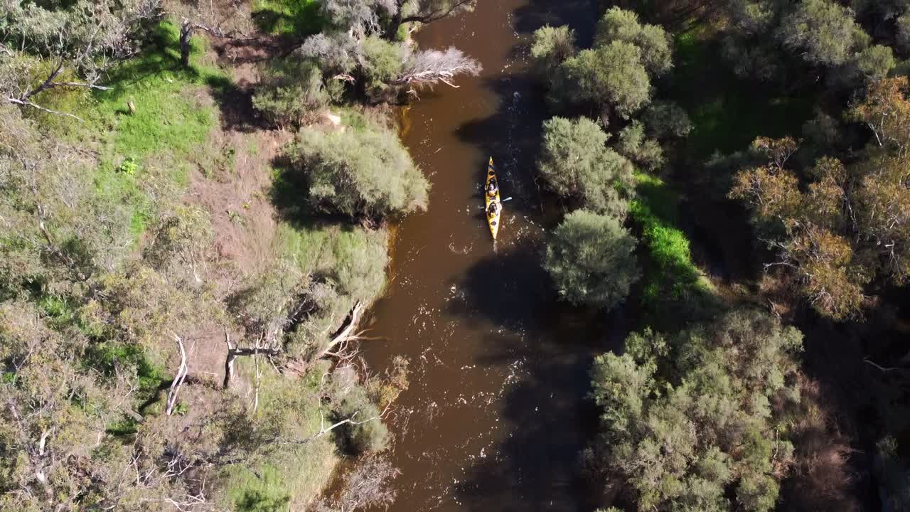 el kayak gemelo viaja por un río estrecho rodeado de vegetación, aérea
