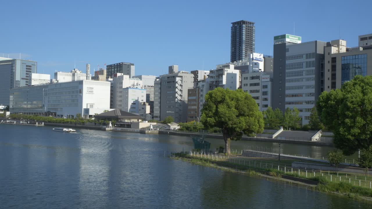 Modern High-rise Buildings Along The O River With Nakanoshima Park From Tenjin Bridge In Kita Ward, Osaka, Japan. - wide shot