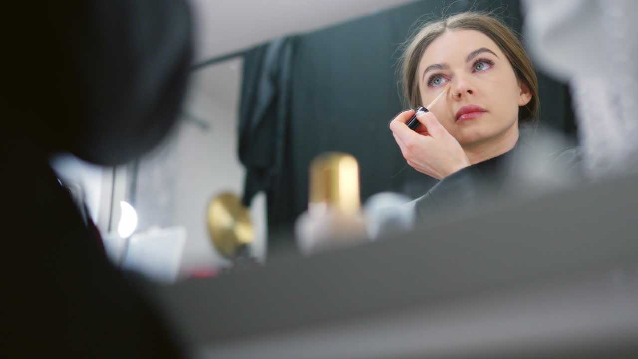 mujer aplicando maquillaje frente a un espejo