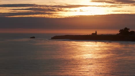 Drohnenaufnahme-Zur-Goldenen-Stunde-Mit-Schwenk-Nach-Rechts-Von-Surfern-Und-Wellen-Bei-Sonnenuntergang