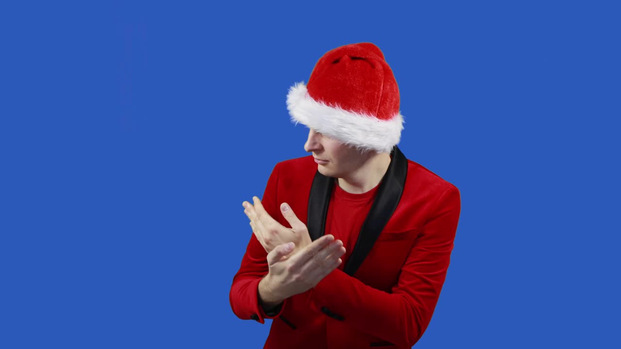 파란 스크린 배경에서 산타클로스처럼 춤을 추는 남자, 타임스, 크리스마스 및 새해 개념, 할인 및 프로모션, 판매, 빨간 슈트와 모자를 입은 남자가 크로마 키 근처로 이동합니다.