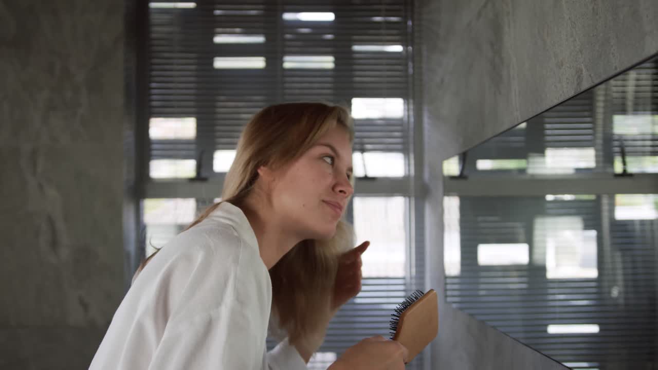 Vista laterale di donna caucasica che si spazzola i capelli in hotel