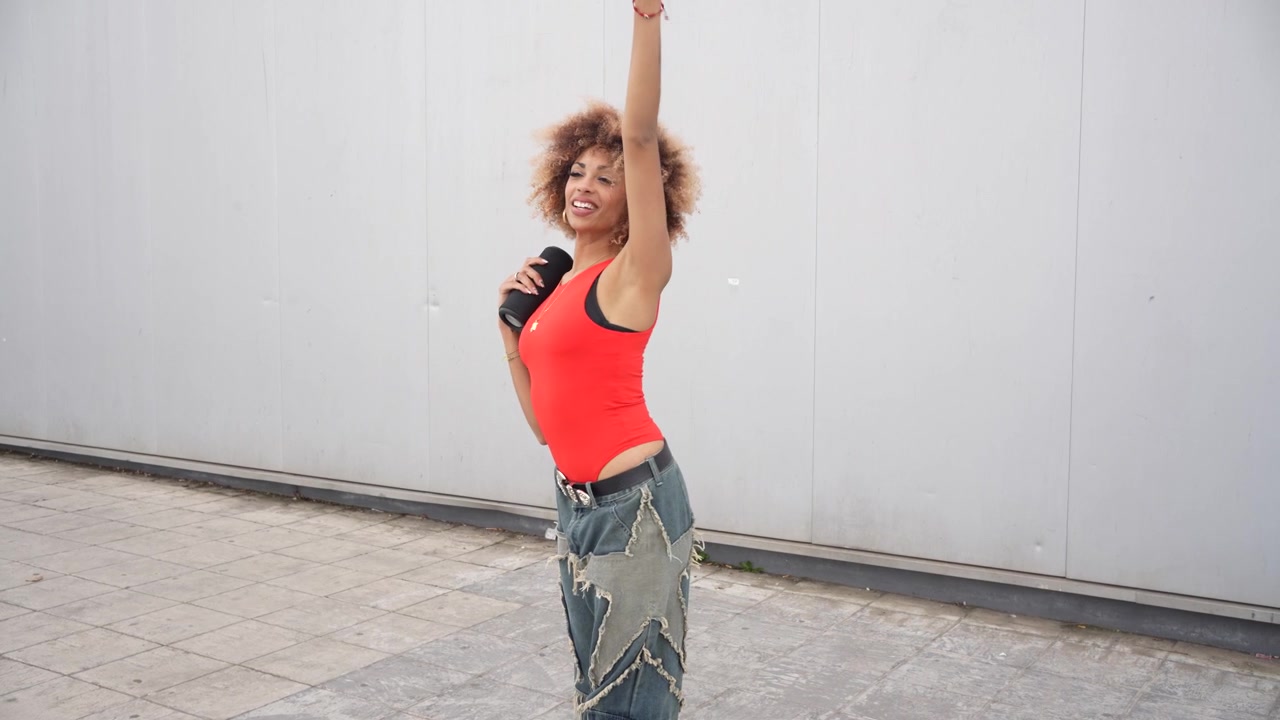 A dynamic dance pose captured of a young woman with curly hair in an urban setting