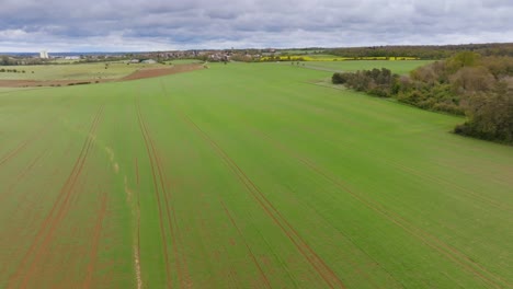 drone shot over a cultivated field and a french village in the distance